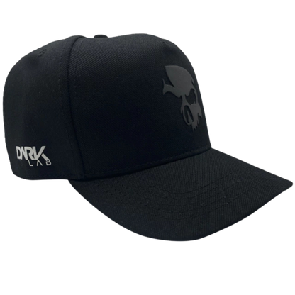 Boné snapback da Dark Lab visto de lado mostrando a logo da marca em uma das laterais e o símbolo de caveira da marca na frente