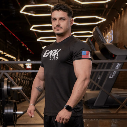 Homem de perfil na academia usando camiseta de caveira para Treino da Dark Lab mostrando o ícone da bandeira americana na manga.