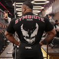 Homem de costas na academia usando a Camiseta Modo Simbionte da Dark Lab mostrando a parte de trás da camiseta com a escrita "Symbiote mode"