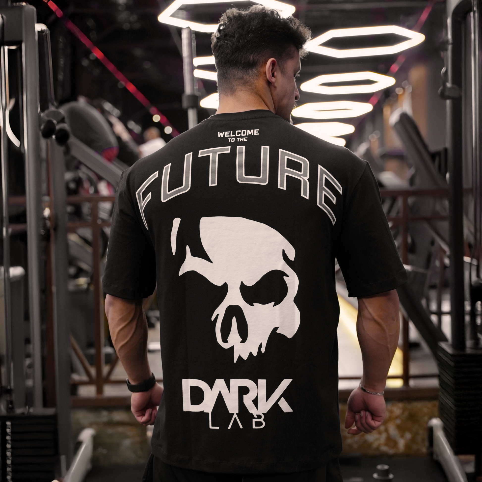 Homem na academia de costas usando a camiseta Welcome To The Future da Dark Lab com a escrita "welcome to the future" e a logo da dark lab na parte de trás.