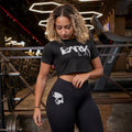 Mulher com academia ao fundo usando o cropped fitness da Dark Lab olhando para baixo 