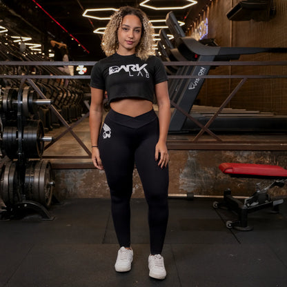 Mulher em um ambiente da academia fazendo pose e usando um cropped fitness para academia com estampa da Dark Lab