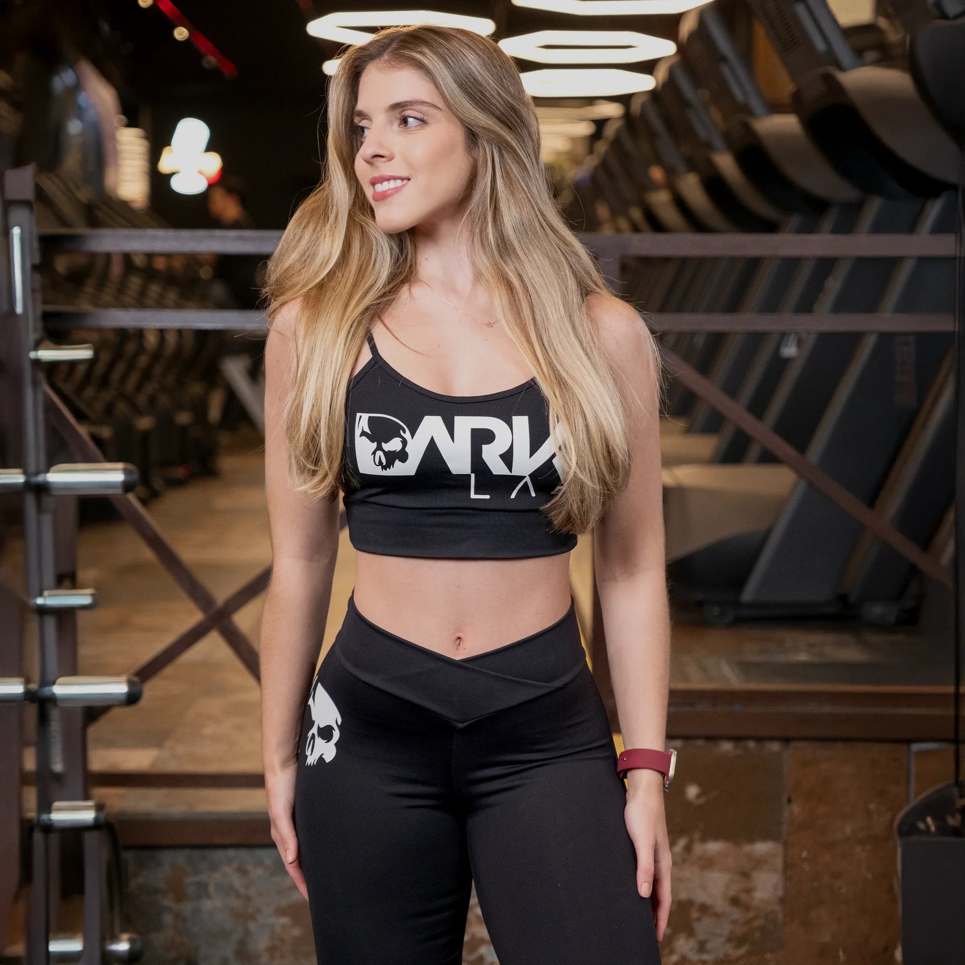 Mulher em academia usando Top para Academia fitness com Bojo Removível da marca Dark Lab com a logo da marca estampada na parte frontal da peça.
