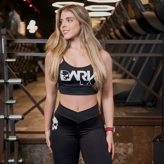 Mulher em academia usando Top para Academia fitness com Bojo Removível da marca Dark Lab com a logo da marca estampada na parte frontal da peça.