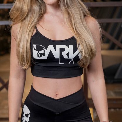 busto de mulher em academia com foco no Top para Academia fitness com Bojo Removível da marca Dark Lab que ela está usando com a logo da marca estampada na parte frontal da peça.